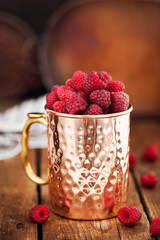 Fresh ripe raspberries in a copper mug