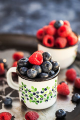 Fresh ripe blueberry and raspberry in mugs