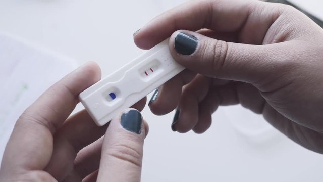 Woman holding a pregnancy test in her hands. The result is positive.