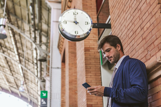 Businessman Using a Mobile Phone at the Train Station