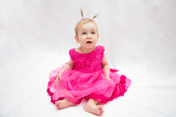 beautiful baby girl in pink dress with pigtails on head on white isolated background