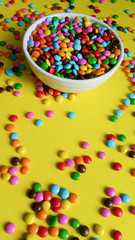 colorful confetti scattered on yellow background (vertical photo)