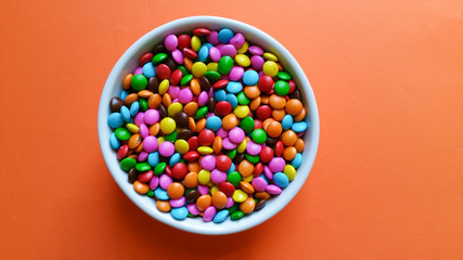 Colorful confetti with orange background top view