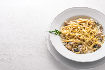Pasta with chicken and mushrooms. Italian cuisine. On a wooden background. Top view. Free space for text.