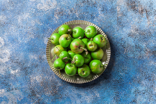 Green Organic Apples Overhead On Silver Plate And Painted Blue Background In Studio