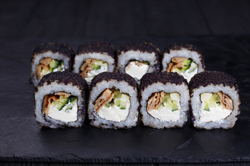 Tasty appetizing uramaki sushi roll with smoked eel, covered with black caviar. Restaurant menu, Japanese food art