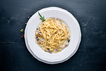 Pasta with chicken and mushrooms. Italian cuisine. On a wooden background. Top view. Free space for text.