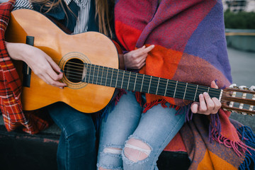 Playing guitar and meeting on roof, close up. Two girls studying music together, unusual places for rest and communication, sharing time in close and cheerful atmosphere concept