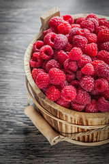 Bucket with fresh raspberries on wooden board