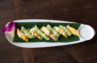 mango sticky rice on banana leaf topped with sweet sauce from above