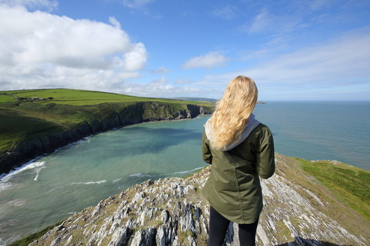 rear view of young blonde girl overlooking St. George's channel at Mwnt beach in Wales, UK