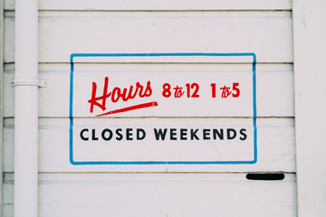 store hours painted on outside wall