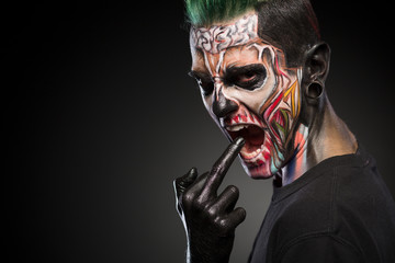 Scary zombie makeup on mans face isolated on black background. Face art, man with monster face.
