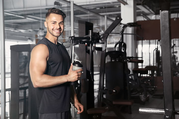 Fototapeta na wymiar Sporty young man with bottle of water in gym