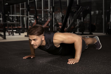 Fototapeta na wymiar Young sporty man doing push ups in gym