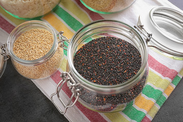 Jars with different quinoa seeds on table