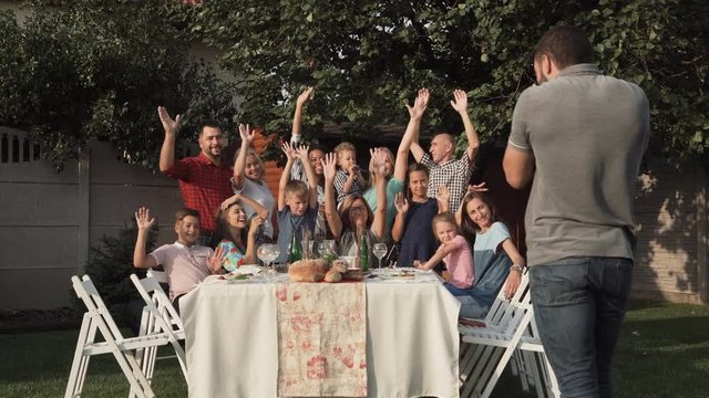 Big happy family posing with hands up for group photo in the garden.