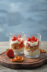 Glasses with strawberry pretzel salad on wooden board