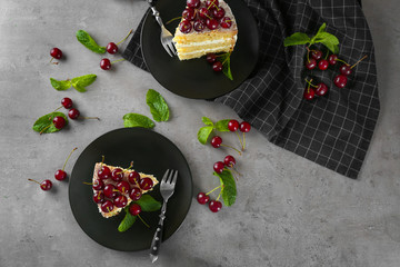 Piece of cake decorated with cherries on plate