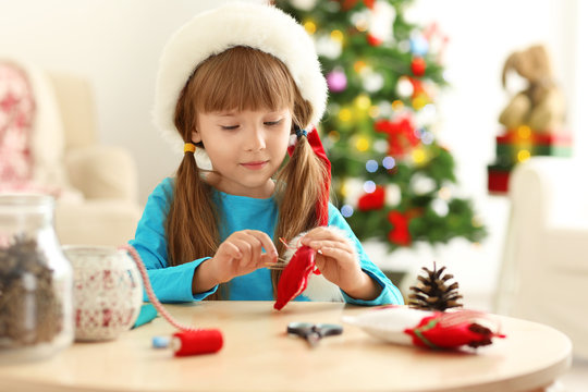 Little girl making Christmas decoration at table