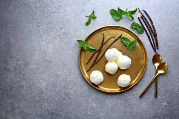Golden plate with yummy vanilla ice cream on table