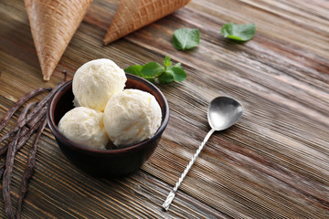 Bowl with yummy vanilla ice cream on wooden table