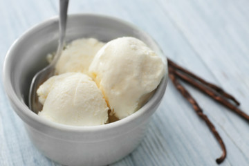 Bowl with yummy vanilla ice cream on wooden table