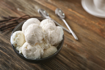 Bowl with yummy vanilla ice cream balls on wooden table