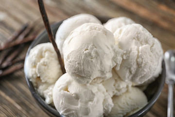 Bowl with yummy vanilla ice cream balls on table, closeup