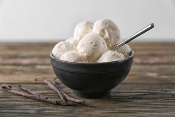Bowl with yummy vanilla ice cream balls on wooden table