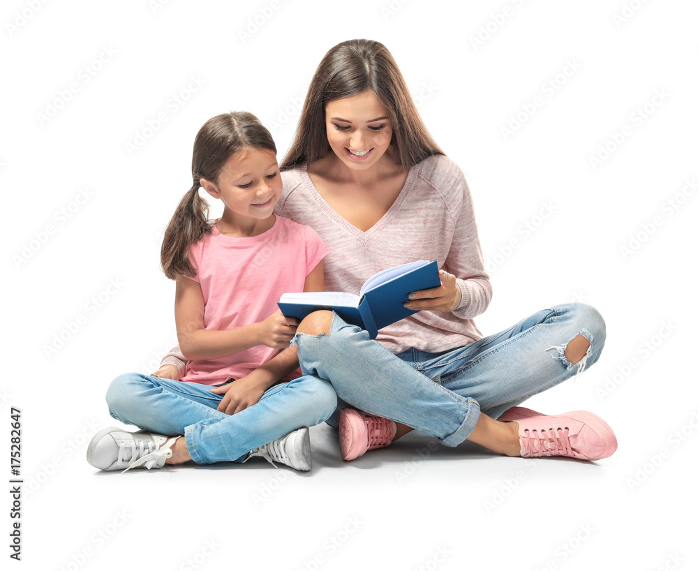 Canvas Prints young woman and her little daughter reading book on white background