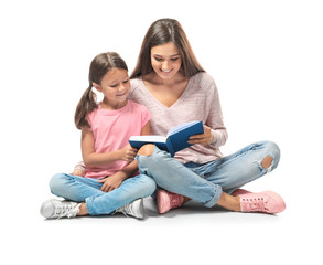 Young woman and her little daughter reading book on white background