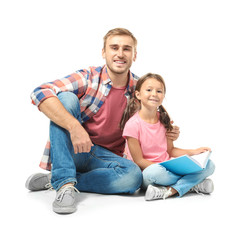 Young man and his little daughter reading book on white background