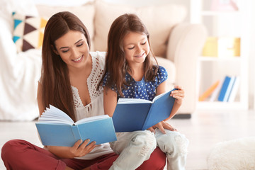 Young woman and her little daughter reading books at home
