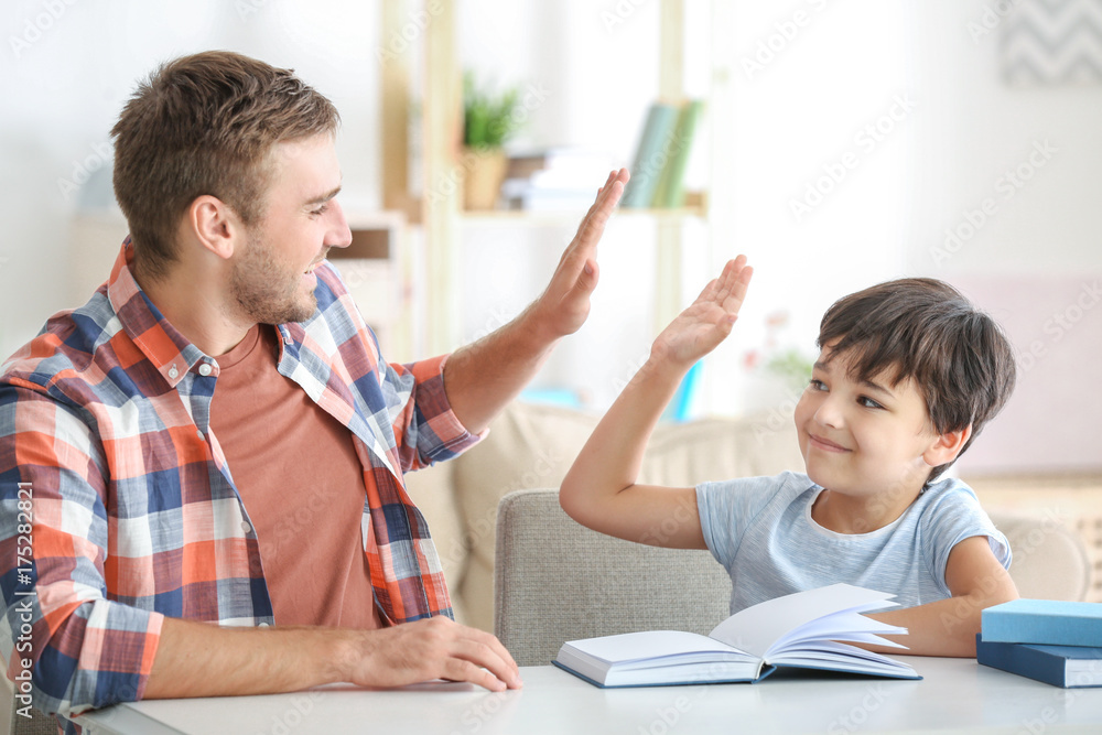 Poster young man and his little son reading book at home