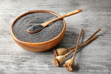 Poppy seeds and dried pods on wooden background