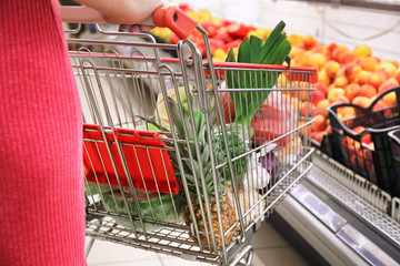 Young woman with shopping cart in supermarket