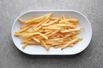 Plate with yummy french fries on kitchen table