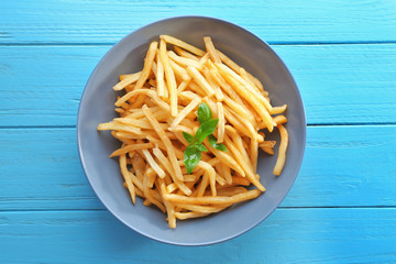 Plate with yummy french fries on wooden table