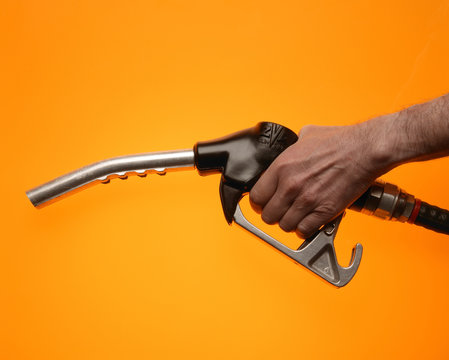 Hand holding petrol pump on yellow background