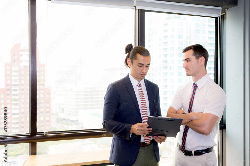 Wall mural Asian young businessman two people holding clipboard and discussing work in the meeting room, business concept.