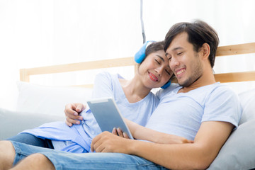 Obraz premium Beautiful asian young couple listening to music with tablet on bed, Love, dating,Young couple in sitting together in bed using a Tablet.