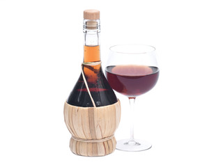 Red pomegranate wine in glass and straw wine bottle isolated on white background