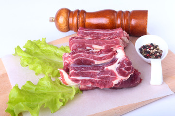 Raw beef edges, lettuce leaf, pepper grinder and spices on wooden desk isolated on white background from above and copy space. ready for cooking.