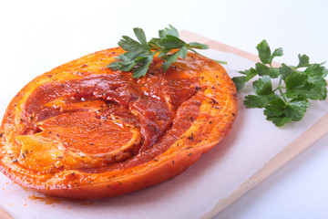 Raw Pork ham with spices and parsley leaves ready for BBQ grilling isolated on white background.