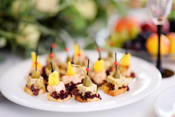 Delicious canape snacks with pineapple and capers topping served on a party or wedding reception