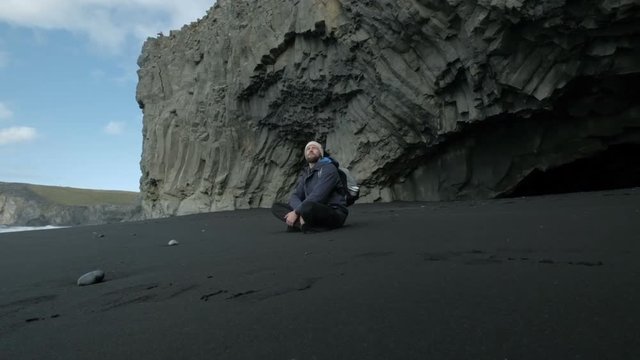 Man sitting by the dark sea - winter scenery from Iceland