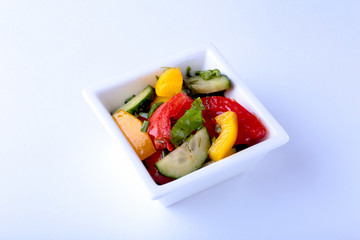 fresh vegetable salad with tomato, cucumber, bell pepper and lettuce leaf in white bowl.
