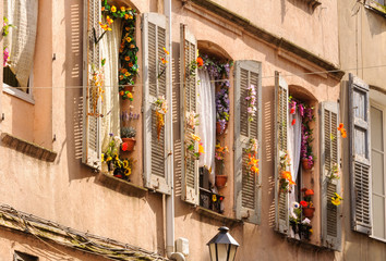 Windows and shutters decorated with colorful fake flowers - Grasse, France