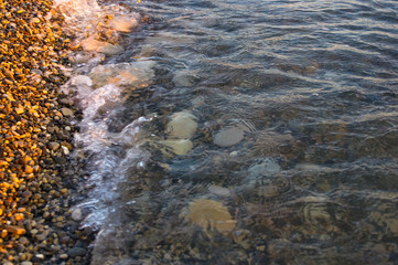 sea pebble beach with multicoloured stones, waves with foam
